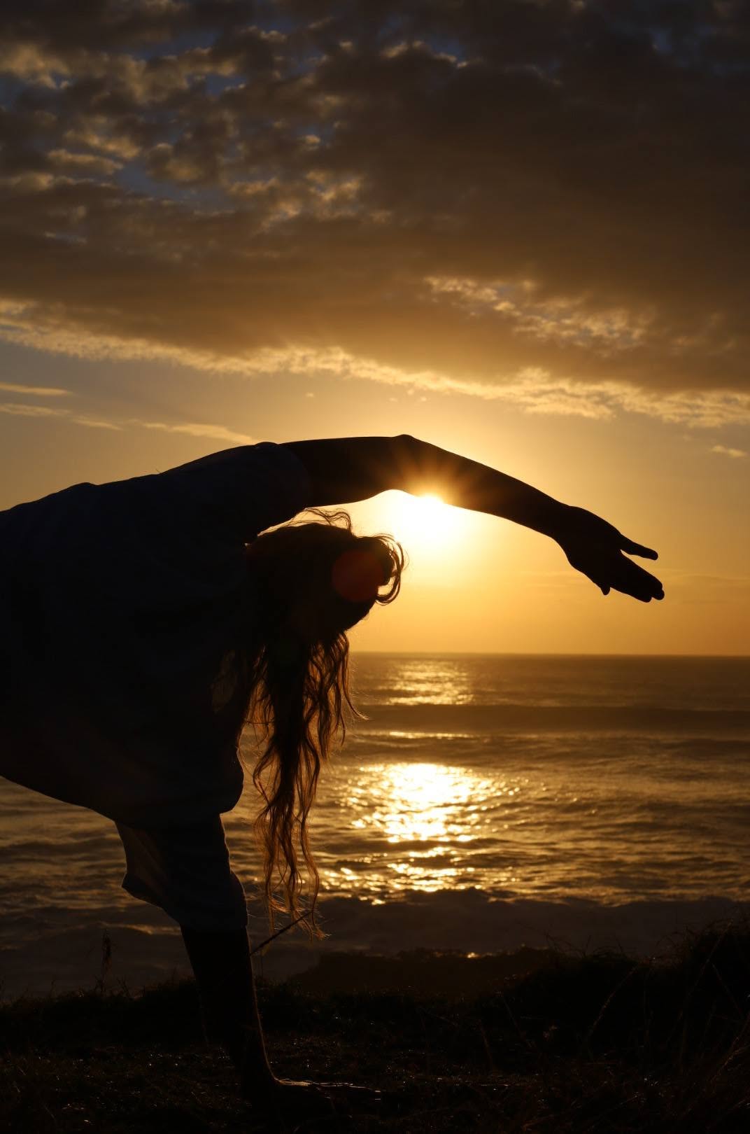 Nic in a deep standing backbend silhouette at sunset