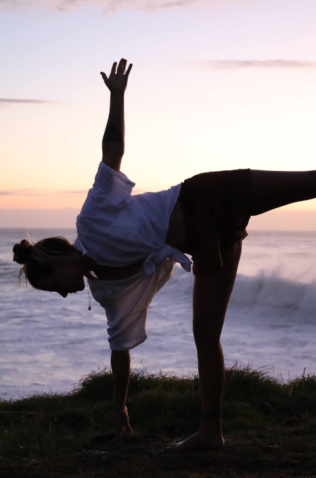 Nic in half-moon pose on a headland at sunset
