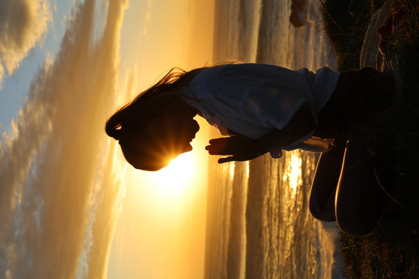 Nic meditating in front of the setting sun over the ocean