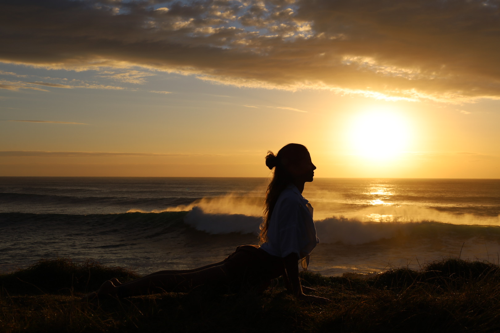 Nic in upward dog on a coastal cliff at sunrise